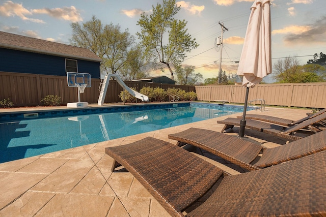 701 Oak Ave, Olivia, MN 56277 - pool at dusk with a water slide and a fenced backyard