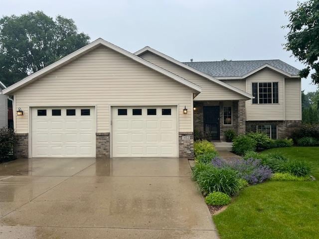 302 Peifer Dr, Litchfield, MN 55355 - view of front facade with concrete driveway, an attached garage, a front yard, and brick siding