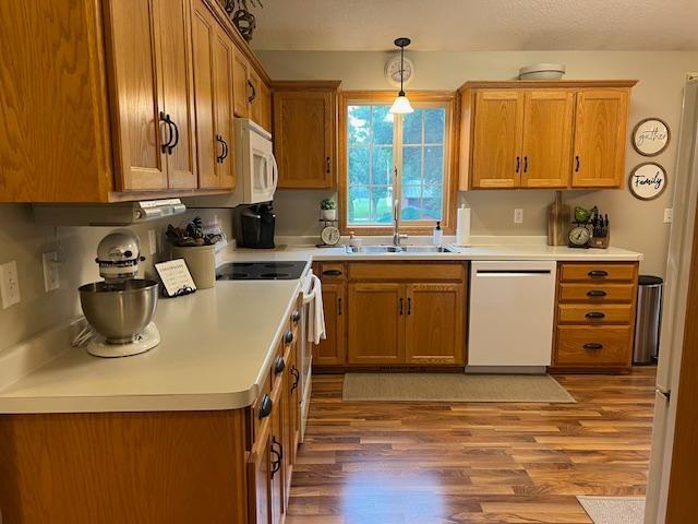 302 Peifer Dr, Litchfield, MN 55355 - kitchen featuring white appliances, wood finished floors, brown cabinets, decorative light fixtures, and light countertops