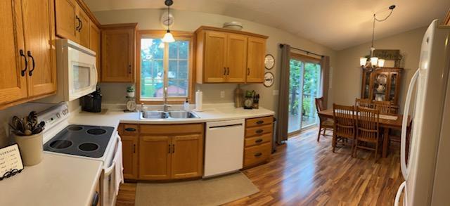 302 Peifer Dr, Litchfield, MN 55355 - kitchen with white appliances, a chandelier, lofted ceiling, dark wood finished floors, and light countertops