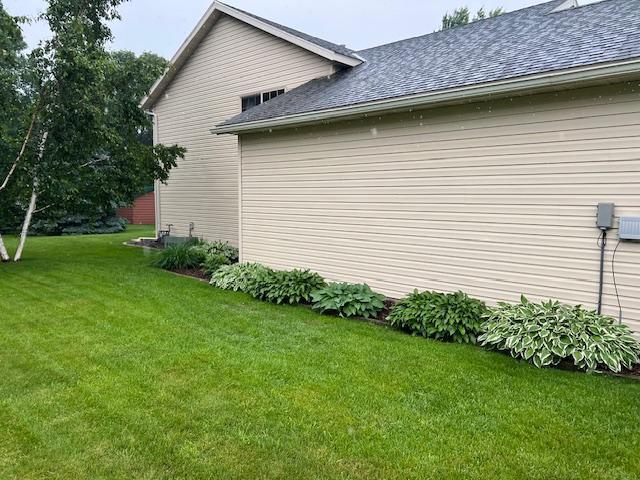 302 Peifer Dr, Litchfield, MN 55355 - view of side of property with a shingled roof and a yard