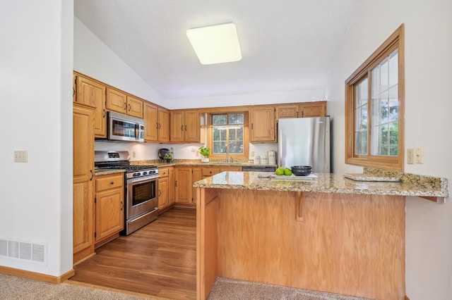 6936 Lake Ter E, Woodbury, MN 55125 - kitchen featuring appliances with stainless steel finishes, a peninsula, light stone countertops, vaulted ceiling, and a breakfast bar area