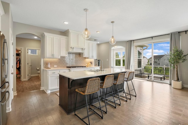 18175 61st Ave N, Plymouth, MN 55446 - kitchen with arched walkways, light countertops, wood-type flooring, an island with sink, and gas stovetop