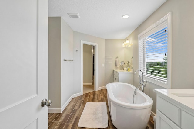 18175 61st Ave N, Plymouth, MN 55446 - full bath featuring two vanities, a soaking tub, wood finished floors, and a textured ceiling