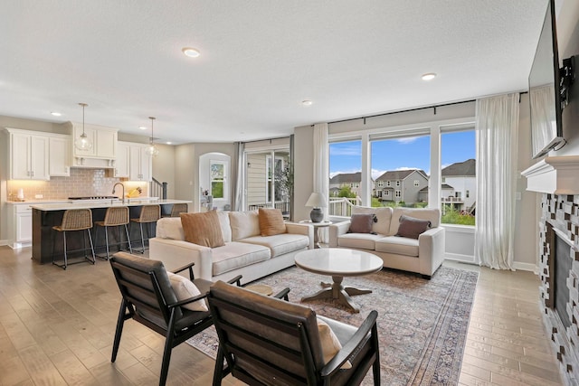 18175 61st Ave N, Plymouth, MN 55446 - living area featuring a fireplace, light wood finished floors, recessed lighting, arched walkways, and a textured ceiling