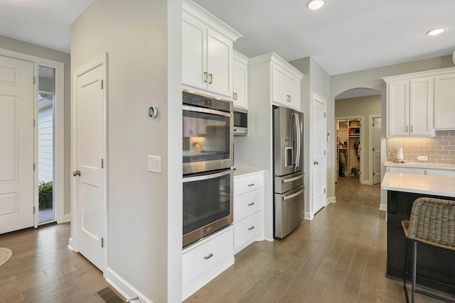 18175 61st Ave N, Plymouth, MN 55446 - kitchen with stainless steel appliances, light countertops, arched walkways, backsplash, and wood finished floors