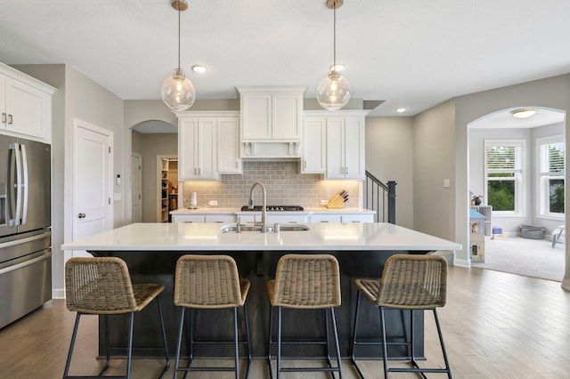 18175 61st Ave N, Plymouth, MN 55446 - kitchen featuring stainless steel appliances, arched walkways, a kitchen island with sink, light countertops, and recessed lighting