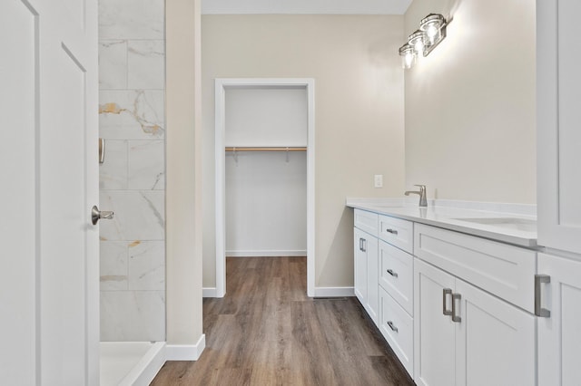 1720 Summer Ln NE, Alexandria, MN 56308 - bathroom featuring double vanity, wood finished floors, a tile shower, and a spacious closet