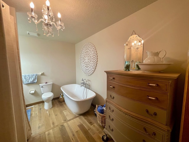 4887 Tee Ct SW, Rochester, MN 55902 - bathroom featuring a chandelier, wood finished floors, vanity, a soaking tub, and a textured ceiling