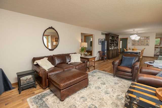 4887 Tee Ct SW, Rochester, MN 55902 - living room with a wood stove, wood finished floors, a chandelier, and a textured ceiling