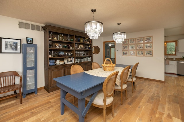 4887 Tee Ct SW, Rochester, MN 55902 - dining room featuring a chandelier, light wood-style flooring, and a textured ceiling