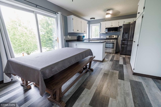 6354 151st Street Ct N, Hugo, MN 55038 - kitchen featuring black microwave, stainless steel gas range oven, refrigerator with ice dispenser, dark wood-style floors, and white cabinetry