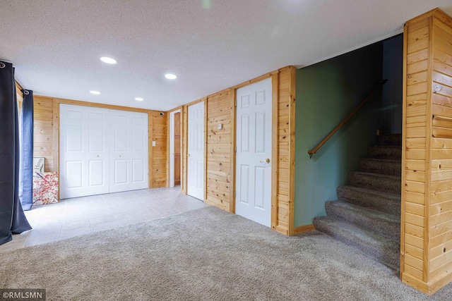 6354 151st Street Ct N, Hugo, MN 55038 - below grade area with wood walls, recessed lighting, a textured ceiling, stairs, and carpet