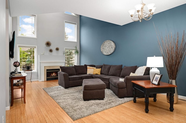 6715 158th St W, Apple Valley, MN 55124 - living room featuring light wood-type flooring, a chandelier, a lit fireplace, and a high ceiling