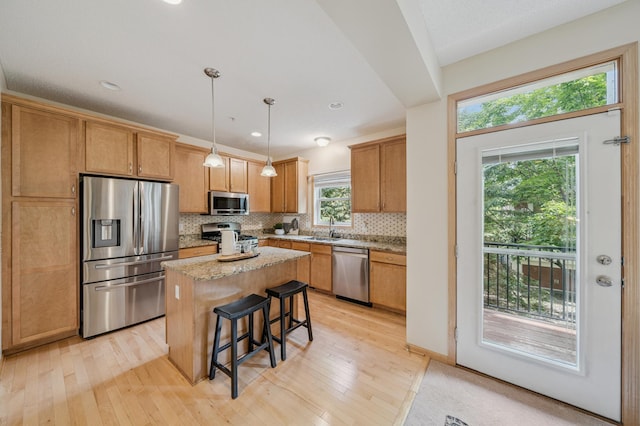 10751 Falling Water Ln Unit C, Woodbury, MN 55129 - kitchen featuring stainless steel appliances, backsplash, light wood-style floors, a kitchen island, and a kitchen bar