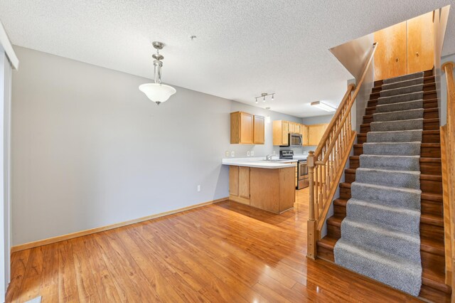 18267 Coneflower Ln, Eden Prairie, MN 55346 - kitchen featuring stainless steel appliances, a peninsula, light wood finished floors, a textured ceiling, and light brown cabinets