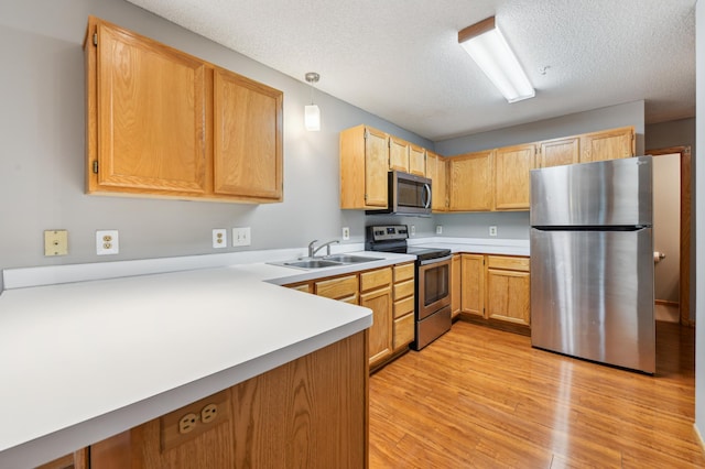 18267 Coneflower Ln, Eden Prairie, MN 55346 - kitchen featuring stainless steel appliances, light countertops, light wood-type flooring, a peninsula, and a textured ceiling