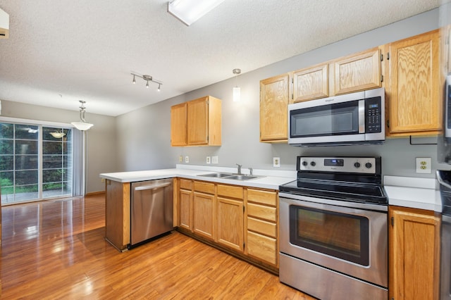 18267 Coneflower Ln, Eden Prairie, MN 55346 - kitchen with appliances with stainless steel finishes, a peninsula, light wood-style floors, light countertops, and a textured ceiling