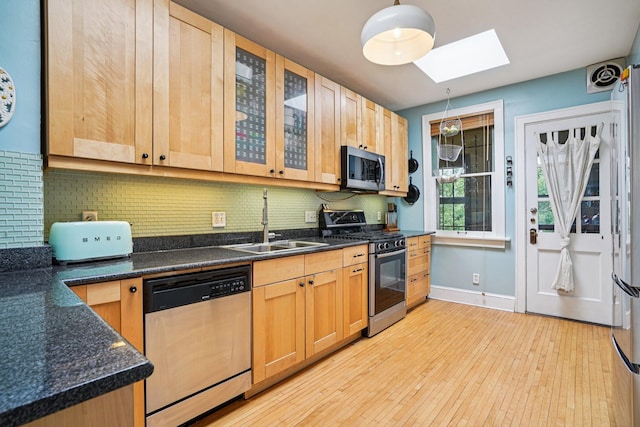 1718 Clinton Ave Unit 6, Minneapolis, MN 55404 - kitchen featuring stainless steel appliances, a skylight, decorative backsplash, light wood-style floors, and glass insert cabinets