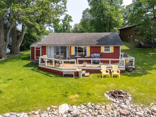 13506 Elmer Hanson Dr SE, Woodside Twp, MN 56736 - rear view of property featuring a fire pit, a wooden deck, a lawn, a storage unit, and a shingled roof