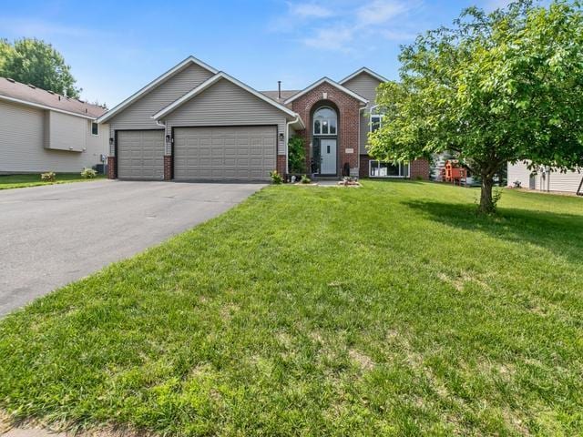 1813 Canton Rd, Prescott, WI 54021 - view of front of house featuring brick siding, a front yard, asphalt driveway, and an attached garage