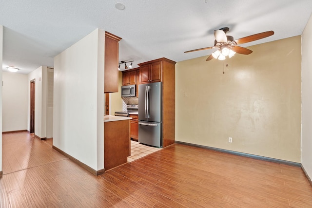2801 Flag Ave N Unit 314, New Hope, MN 55427 - kitchen featuring appliances with stainless steel finishes, ceiling fan, light wood finished floors, tasteful backsplash, and brown cabinets