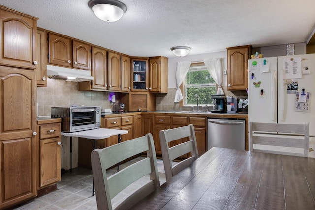 1388 13 1/2 Ave, Barron, WI 54812 - kitchen with dishwasher, under cabinet range hood, white fridge with ice dispenser, brown cabinetry, and backsplash
