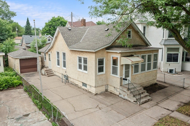 693 Bedford St, Saint Paul, MN 55130 - view of front of property featuring a shingled roof, an outbuilding, a detached garage, concrete driveway, and stucco siding