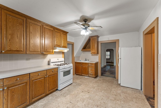 693 Bedford St, Saint Paul, MN 55130 - kitchen with white appliances, under cabinet range hood, brown cabinets, ceiling fan, and backsplash