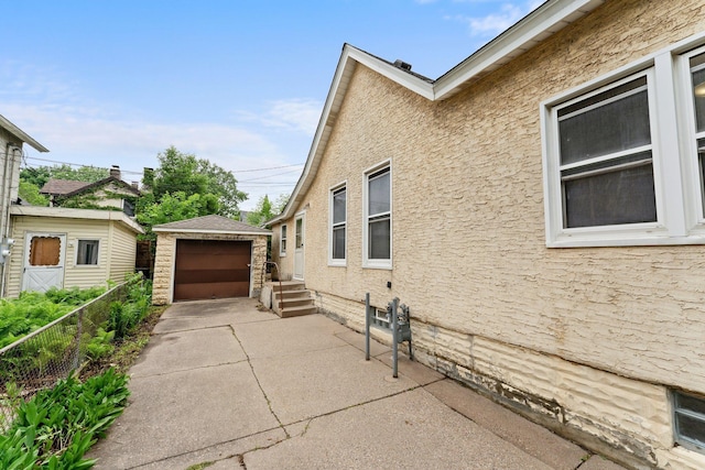 693 Bedford St, Saint Paul, MN 55130 - view of side of property with driveway, an outdoor structure, a detached garage, and stucco siding