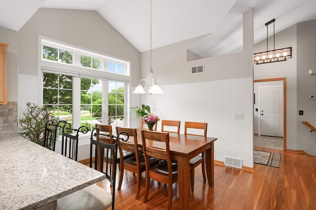 10787 Alison Way, Inver Grove Heights, MN 55077 - dining space featuring a chandelier, wainscoting, light wood-type flooring, and high vaulted ceiling