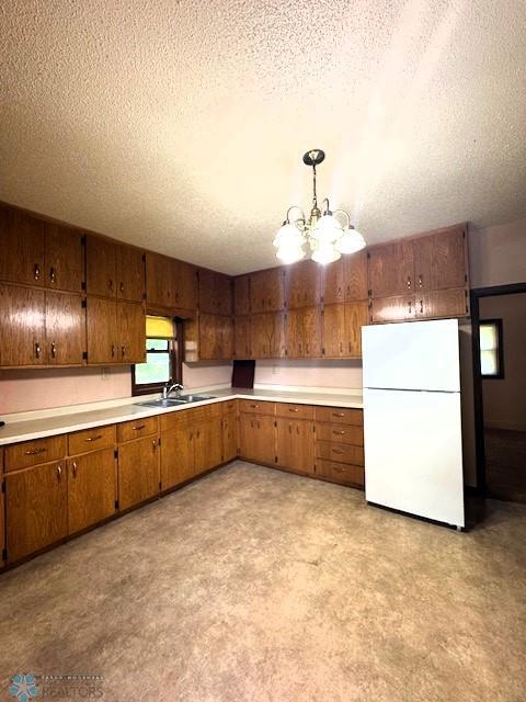 857 Main St, Mahnomen, MN 56557 - kitchen with freestanding refrigerator, brown cabinetry, a textured ceiling, and light countertops