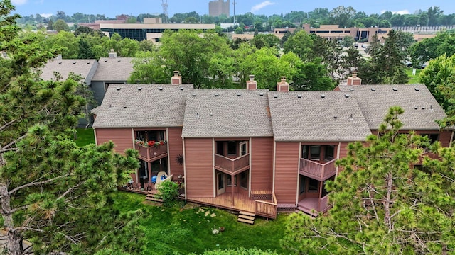 1369 Spencer Rd W, Saint Paul, MN 55108 - back of house with a chimney, view of scattered trees, roof with shingles, and a balcony