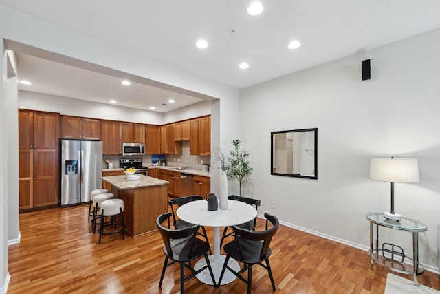 5900 Oxford St Unit 8, Saint Louis Park, MN 55416 - kitchen with appliances with stainless steel finishes, light wood-style flooring, a kitchen island, tasteful backsplash, and a kitchen bar