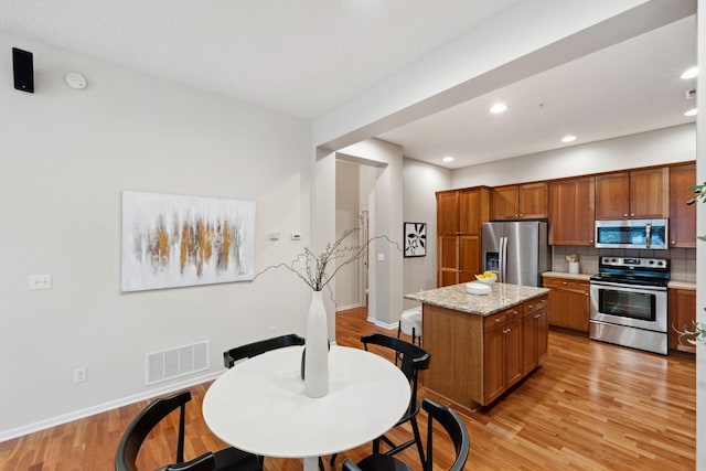 5900 Oxford St Unit 8, Saint Louis Park, MN 55416 - kitchen featuring appliances with stainless steel finishes, brown cabinets, light wood-style flooring, backsplash, and recessed lighting