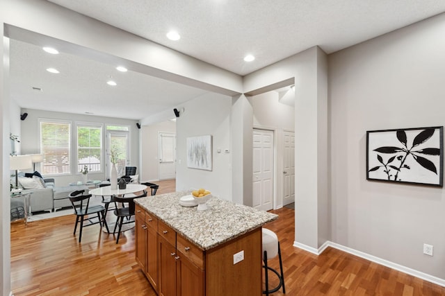 5900 Oxford St Unit 8, Saint Louis Park, MN 55416 - kitchen featuring light wood finished floors, a kitchen island, brown cabinetry, a kitchen breakfast bar, and open floor plan
