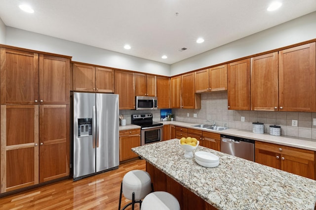 5900 Oxford St Unit 8, Saint Louis Park, MN 55416 - kitchen featuring stainless steel appliances, brown cabinets, a kitchen breakfast bar, light wood-style flooring, and backsplash
