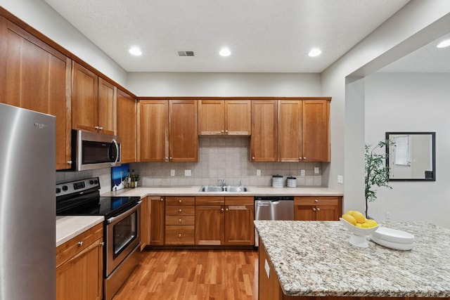 5900 Oxford St Unit 8, Saint Louis Park, MN 55416 - kitchen featuring stainless steel appliances, light wood-type flooring, brown cabinetry, backsplash, and light stone counters