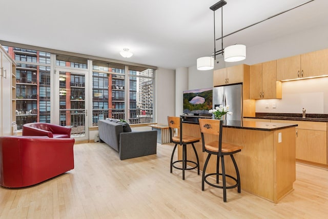 215 10th Ave S Unit 533, Minneapolis, MN 55415 - kitchen featuring stainless steel fridge with ice dispenser, light wood finished floors, dark countertops, a kitchen island, and expansive windows