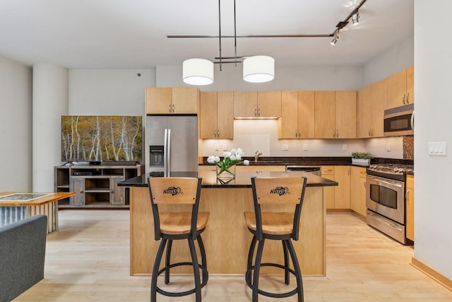 215 10th Ave S Unit 533, Minneapolis, MN 55415 - kitchen with appliances with stainless steel finishes, light brown cabinetry, light wood-type flooring, and dark countertops