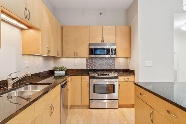 215 10th Ave S Unit 533, Minneapolis, MN 55415 - kitchen featuring appliances with stainless steel finishes, light brown cabinets, dark stone countertops, and backsplash