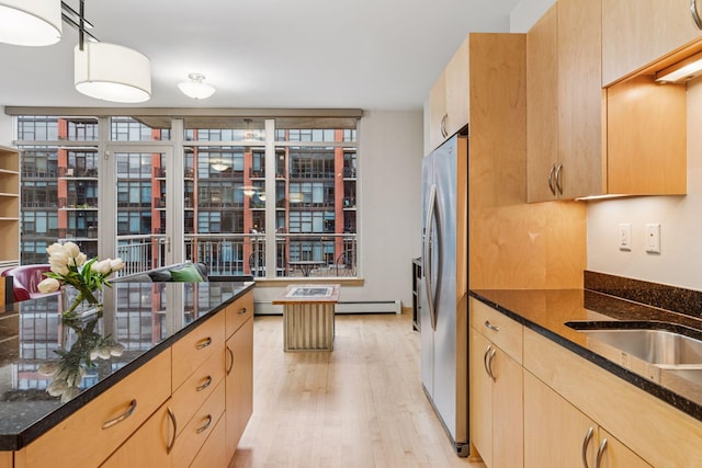 215 10th Ave S Unit 533, Minneapolis, MN 55415 - kitchen featuring light brown cabinetry, light wood-style flooring, dark stone countertops, and decorative light fixtures