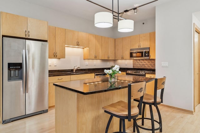 215 10th Ave S Unit 533, Minneapolis, MN 55415 - kitchen with stainless steel appliances, light wood-style floors, light brown cabinetry, a kitchen breakfast bar, and a kitchen island