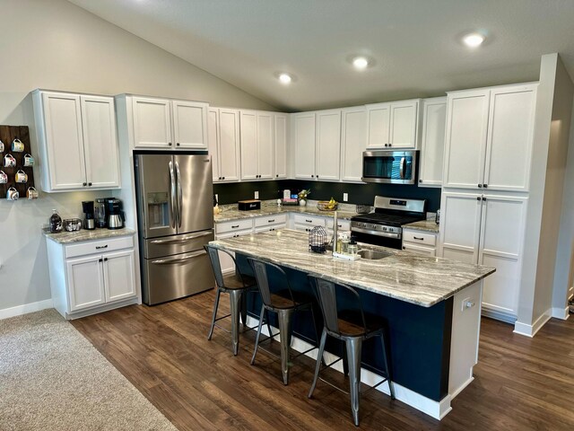 7559 Oday Ln NE, Otsego, MN 55330 - kitchen with stainless steel appliances, vaulted ceiling, white cabinets, dark wood-style flooring, and a kitchen bar