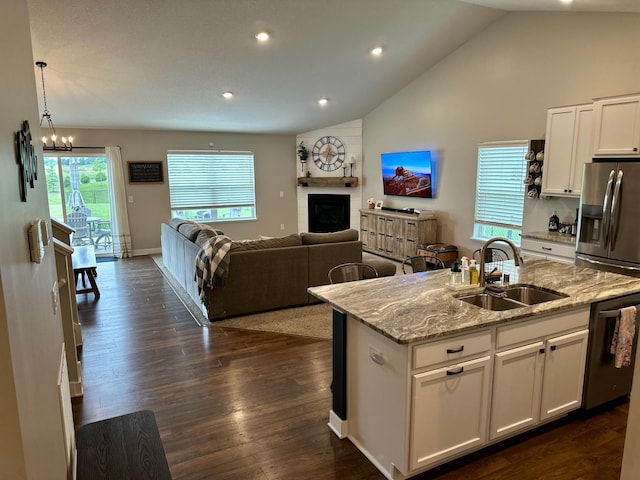 7559 Oday Ln NE, Otsego, MN 55330 - kitchen featuring stainless steel appliances, lofted ceiling, white cabinetry, open floor plan, and light stone counters