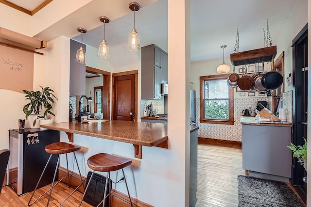 2707 Brighton Ave NE, Minneapolis, MN 55418 - kitchen with wood finished floors, a kitchen bar, pendant lighting, and dark countertops