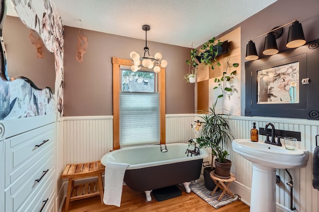 2707 Brighton Ave NE, Minneapolis, MN 55418 - bathroom with a wainscoted wall, wood finished floors, a freestanding bath, a chandelier, and a textured ceiling