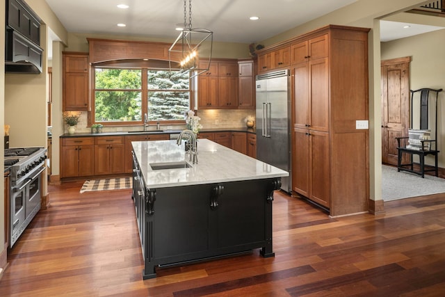 6445 County Road 26, Minnetrista, MN 55364 - kitchen with high end appliances, brown cabinetry, recessed lighting, a kitchen island with sink, and tasteful backsplash
