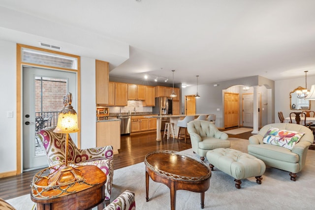 1700 Metro Blvd Unit 210, Edina, MN 55439 - living room featuring dark wood finished floors, arched walkways, track lighting, and a chandelier