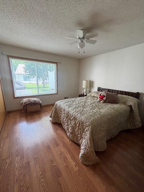 9257 Prairieview Trl N, Champlin, MN 55316 - bedroom with wood finished floors, a textured ceiling, and a ceiling fan